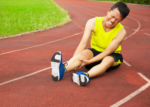 young male runner suffering from leg cramp on the track